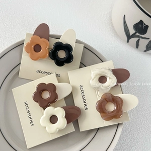 Barrettes à cheveux fleurs aux tons macarons et ambre sur support de présentation