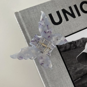 Detail of butterfly hair claw clip with purple marble texture on a stylish magazine