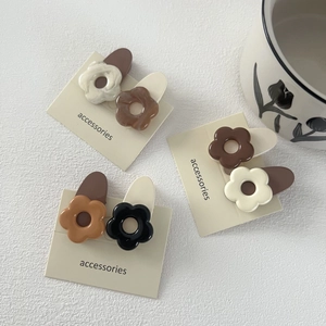 Vue macro détaillée de pinces à cheveux fleur macaron sur un emballage carton épuré