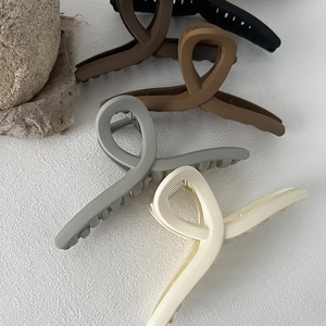 Group of four matte large hair claws in black, coffee, grey and beige on a white surface
