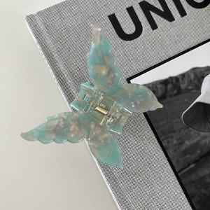 Detail of blue iridescent butterfly hair claw clip with acetate marble texture