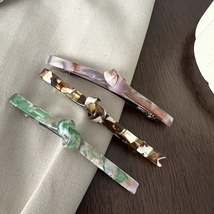 Three acetate bow spring hair clips in marble, tortoiseshell, and lavender patterns
