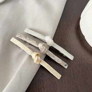 Three-piece set of elegant acetate hair clips in white, marble, and beige with knot detail