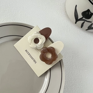 Vue détaillée de deux pinces à cheveux en forme de fleur crème et marron sur carte