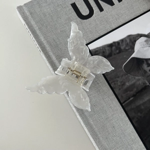 Detail of butterfly hair claw clip with marble texture and premium golden spring