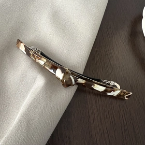 Macro detail of tortoiseshell acetate hair clip with marble texture and silver metal spring