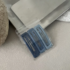 Close-up of three blue gradient snap hair clips with matte finish in clear packaging