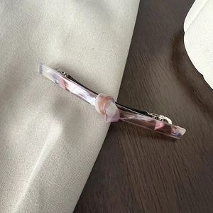 Detailed view of long acetate bow hair clip with purple and pink marble swirl pattern