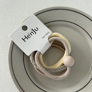 Detailed view of four Morandi colored hair bands on branded card in a ceramic dish