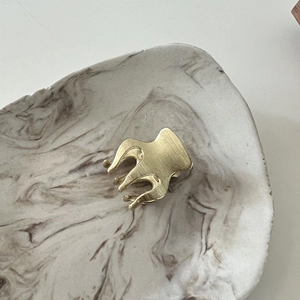 Macro detail of a matte gold metal hair claw clip with a refined brushed texture finish