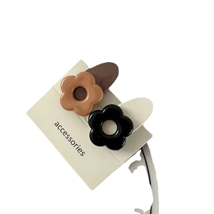 Lot de deux barrettes à cheveux en forme de fleur marron et noire sur carte blanche