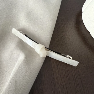 Close-up of cream white acetate hair clip with marble texture and knot design details
