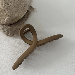 Detail view of the large 13cm matte brown hair claw clip on a minimalist textured surface