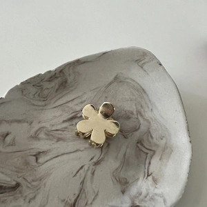 Macro detail of a small golden flower hair claw clip with a matte brushed metal finish