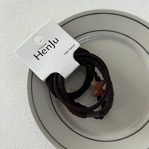 Detailed view of dark brown elastic hair bands set with textured designs and bow charm