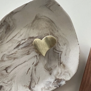 Macro shot of minimalist gold heart hair clip with brushed metal texture and elegant finish