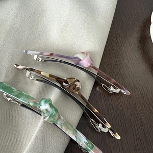 Detailed close-up of acetate bow hair clips in lavender, tortoise, and emerald marble