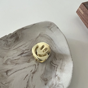 Close-up of a small golden metal hair claw clip featuring a hollow smile face design