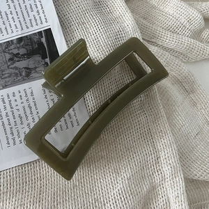Detail einer großen olivgrünen Haarklammer mit glänzendem Finish und hohlem Design