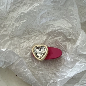 Nahaufnahme einer herzförmigen Kristall-Haarspange mit roter Basis auf weißem Papier