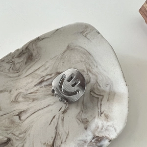 Detailed view of silver metal smile hair claw with brushed texture on marble tray