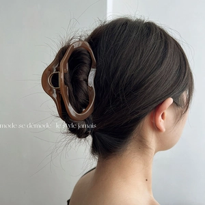 Detail of caramel brown oversized hair claw clip securing a full bun with high gloss finish