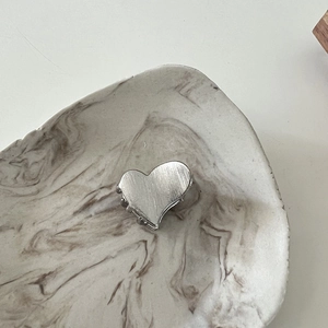 Detailed side view of silver heart-shaped metal hair claw with brushed texture and strong teeth