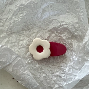 Nahaufnahme einer süßen Haarspange mit cremefarbener Blume auf rosa Harzbasis