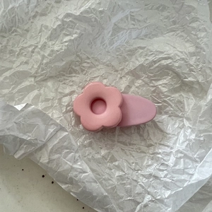 Nahaufnahme einer rosa Blumen-Haarspange mit mattem Harz-Finish auf weißem Papier