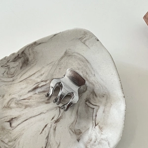 Detailed view of small silver metal hair claw clip with brushed texture on marble tray