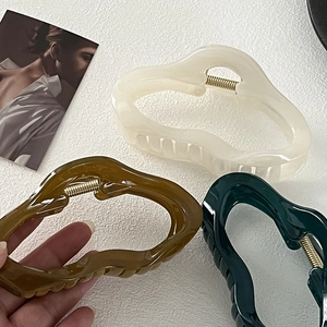 Detailed view of large irregular wave hair claws in cream, brown, and deep green resin