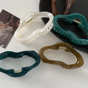 Macro shot of large glossy resin hair claws in Morandi colors with strong metal spring