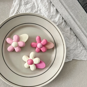 Lot de trois pinces à cheveux fleurs roses et blanches de style coréen sur une assiette