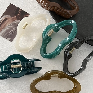 Detailed view of six irregular wavy hair claws in assorted glossy resin colors