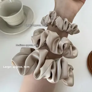 Detailed comparison of three sizes of silk satin hair scrunchies on a wrist