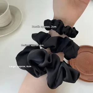 Detailed comparison of small, medium, and large black satin scrunchies showing three sizes
