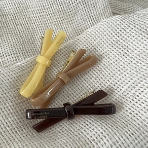 Detailed view of three-piece acetate bow hair clips in yellow and brown tones