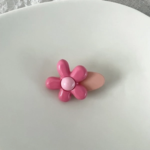 Détail d'une jolie pince à cheveux fleur rose brillante sur une assiette blanche