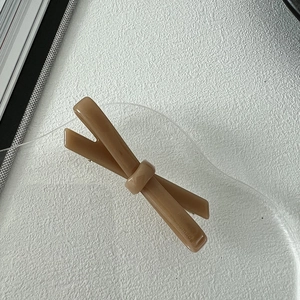 Detail of cream brown acetate bow hair clip with Handmade engraving on white background