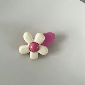 Vue détaillée d'une barrette à fleurs rose et blanche mignonne avec une finition lisse