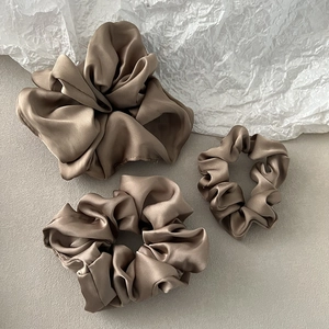 Three-piece set of champagne satin hair scrunchies in various sizes on a neutral background