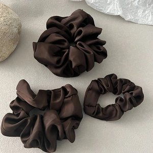Detailed view of three different sizes of smooth dark brown silk satin hair scrunchies