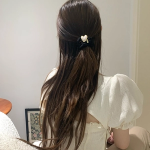 Coletero de terciopelo con dije de corazón perlado mostrado en modelo en entorno natural