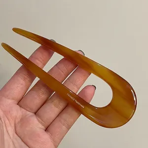 Macro detail of amber U-shaped hair pin featuring gold France Handmade lettering