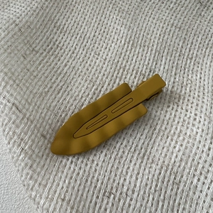 Mustard yellow matte wave edge hair clip on white textured linen background