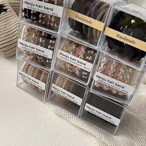 Detail of 8pcs braided hair ties in beige and coffee tones packed in a clear box