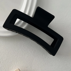 Detail of a large matte black square hair claw clip with a minimalist hollow design