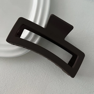 Macro view of matte dark brown rectangular hair claw clip with a hollow geometric frame