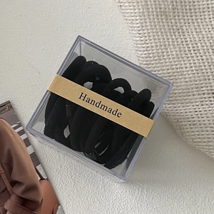 Detail view of premium black seamless hair ties in a square box with a handmade label