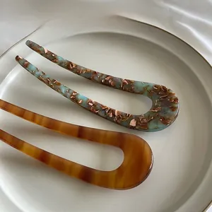 Close-up of marble pattern and tortoiseshell resin hair forks on a ceramic plate